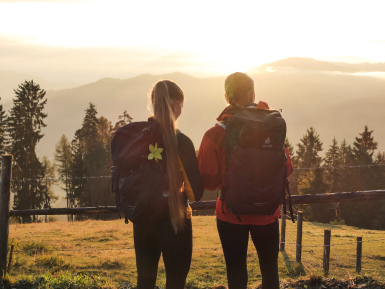 Zwei Wanderer blicken bei Sonnenuntergang vom Magdalensberg